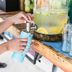 a woman is filling a glass with lemonade