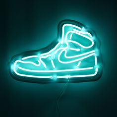 a neon sign with a shoe on it's side hanging from the ceiling in a dark room