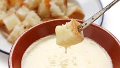 a spoon full of dip being dipped with bread