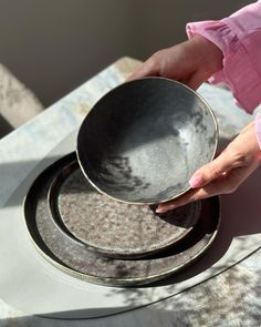 a person is holding a bowl on top of two plates