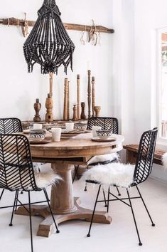 a dining table with four chairs and a chandelier hanging from the ceiling above it