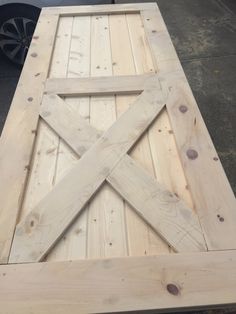 a table made out of wooden planks on top of a cement ground with wheels in the background