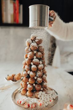 a person is sprinkling sugar on a christmas tree made out of cookies and marshmallows