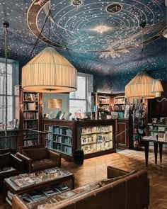 a library with many books on shelves and lamps hanging from the ceiling over it's seating area