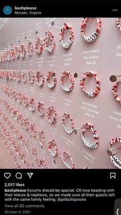 some pink and white beads are hanging on the side of a wall with words written in them