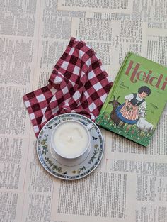 a tea cup and saucer sitting on top of a table next to a book