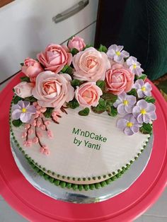 a cake decorated with flowers on top of a pink plate and green trimmings