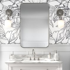 a bathroom vanity with two sinks and a large mirror above it, in front of a floral wallpaper