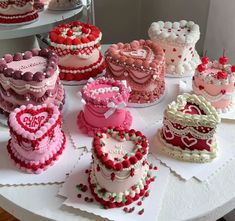 a table topped with lots of cakes covered in pink and red frosting sitting next to each other