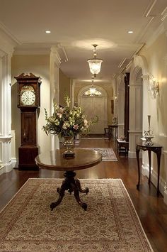 a large wooden table sitting in the middle of a hallway next to a tall clock