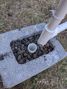 a cup is sitting in the middle of some rocks with a pipe sticking out of it