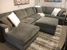 a large sectional couch in a living room with pillows on the floor and other furniture