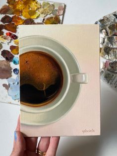 a cup of coffee sitting on top of a white plate next to a piece of paper