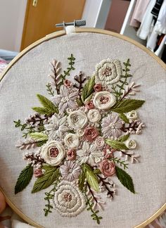 a person holding up a white and pink flower in front of a embroideryed hoop