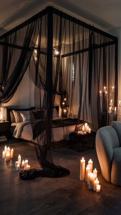 candles are lit on the floor in front of a canopy bed