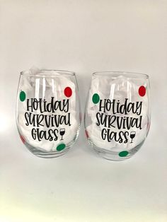 two wine glasses with the words holiday survival glass printed on them, sitting next to each other