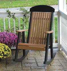 a wooden rocking chair sitting on top of a brick patio next to flowers and plants