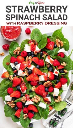 strawberry spinach salad with raspberry dressing is shown on a white platter