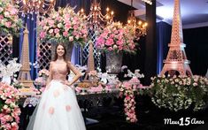 a woman standing in front of a table with pink flowers and chandeliers on it