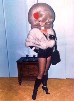 a woman in short shorts and high heels is holding a fur coat over her head