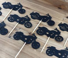 many black cutouts are on sticks with toothpicks in the shape of motorbikes