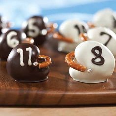 chocolate covered pretzels with numbers on them sitting on a wooden board, ready to be eaten