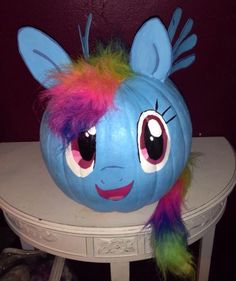 a blue pumpkin with colorful hair on top of a table