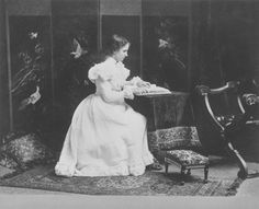 an old photo of a woman sitting at a table in a room with birds flying around