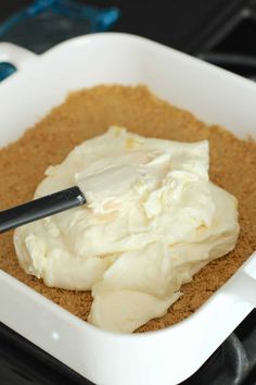 a white dish filled with whipped cream on top of a stove