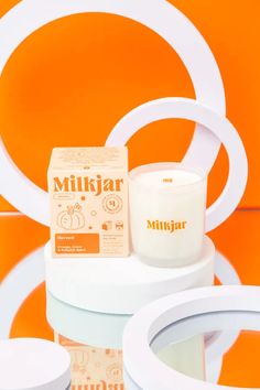 a white candle sitting on top of a table next to an orange and white wall