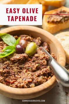 a wooden bowl filled with olives and bread