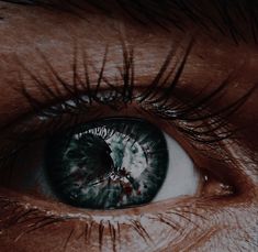 an extreme close up shot of someone's eye with the iris partially open and their eyelashes showing