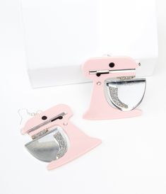 two pink and silver kitchen appliances sitting on top of a white counter next to each other