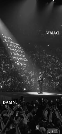 a man standing on top of a stage in front of a crowd with his hands up