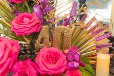 a vase filled with pink flowers sitting next to a candle and some candles on top of a table