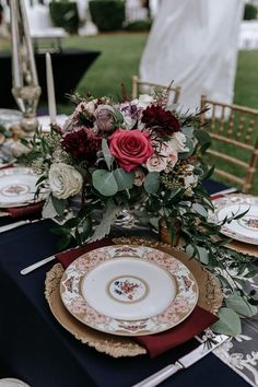 the table is set with plates and place settings for an elegant wedding reception in burgundy, white and gold