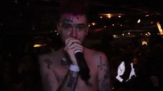 a shirtless man holding a microphone in front of his face with tattoos on it