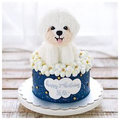 a white dog is sitting on top of a blue birthday cake with stars and flowers