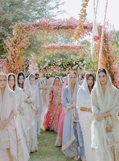 a group of women standing next to each other in front of a flower covered archway