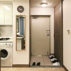 a washer and dryer in a small room next to a doorway with a mirror on the wall