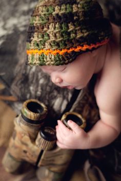 a baby wearing a knitted hat and holding a pair of binoculars in his hands