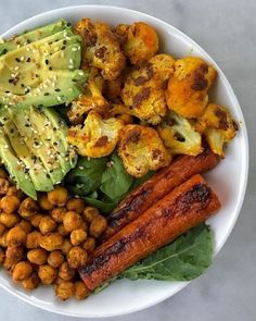 a white plate topped with carrots, avocado and other foodstuffs