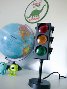 a traffic light sitting on top of a table next to a small green toy dinosaur