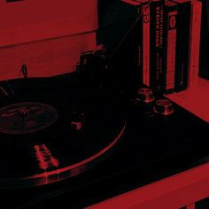 a record player sitting on top of a table next to two books and a remote control