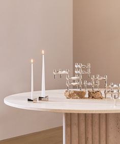 a table with candles on it in front of a white wall and some other items