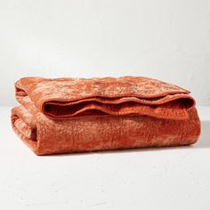 an orange blanket laying on top of a white table