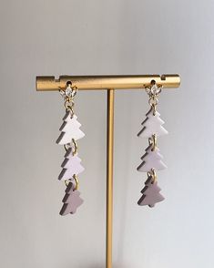 two pairs of earrings with white and pink shapes hanging from gold earwires on a stand