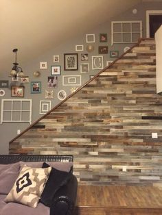 a living room filled with furniture next to a stair case covered in pictures and frames