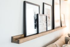 three framed pictures are hanging on the wall above a couch in a room with white walls