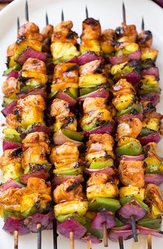 several skewers of food sitting on a white plate with purple cloth around it